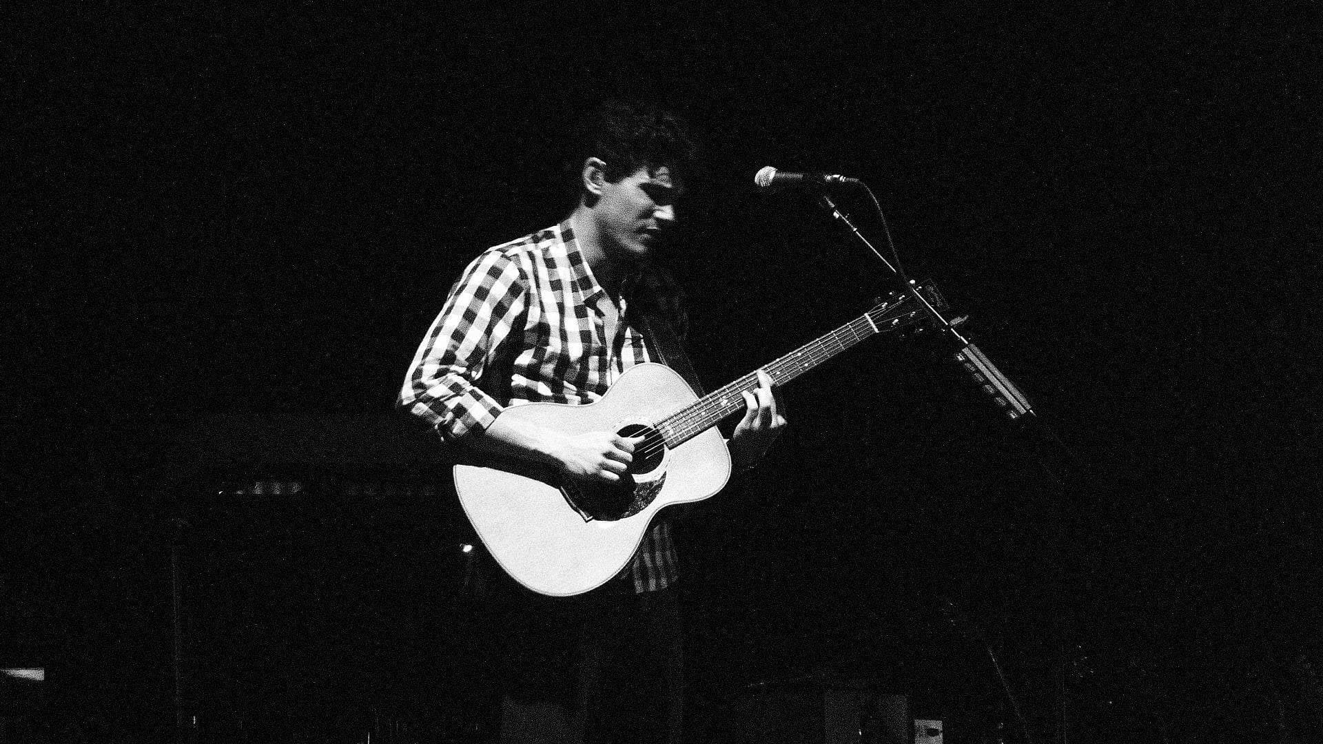 John Mayer black and white playing an acoustic guitar